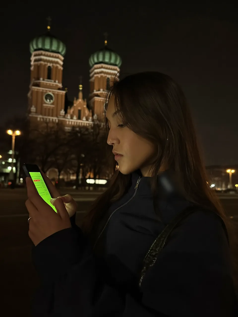 Fahrgast bucht nachts per Smartphone eine Fahrt, im Hintergrund die Türme der Frauenkirche